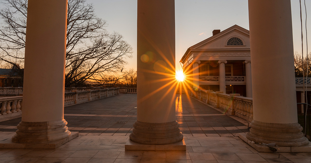 Light from the rising sun is shining behind a column of the Rotunda.